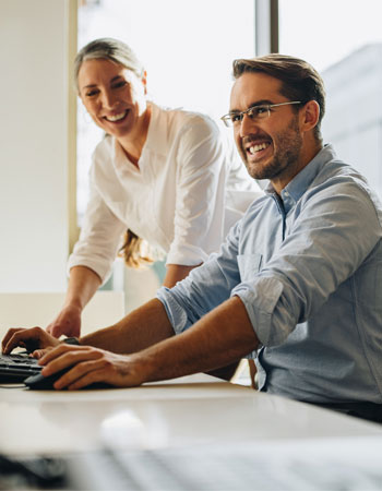 A happy man and woman using a computer - Remote IT support services for small businesses